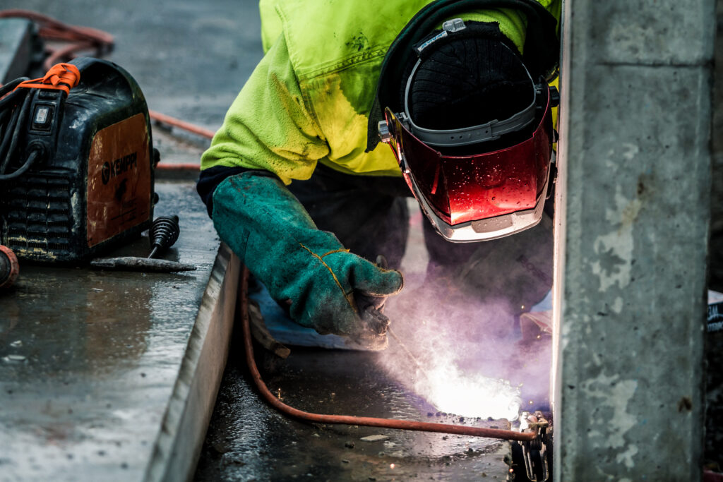 Closeup of a construction worker using a flame torch to cut up heavy machinery