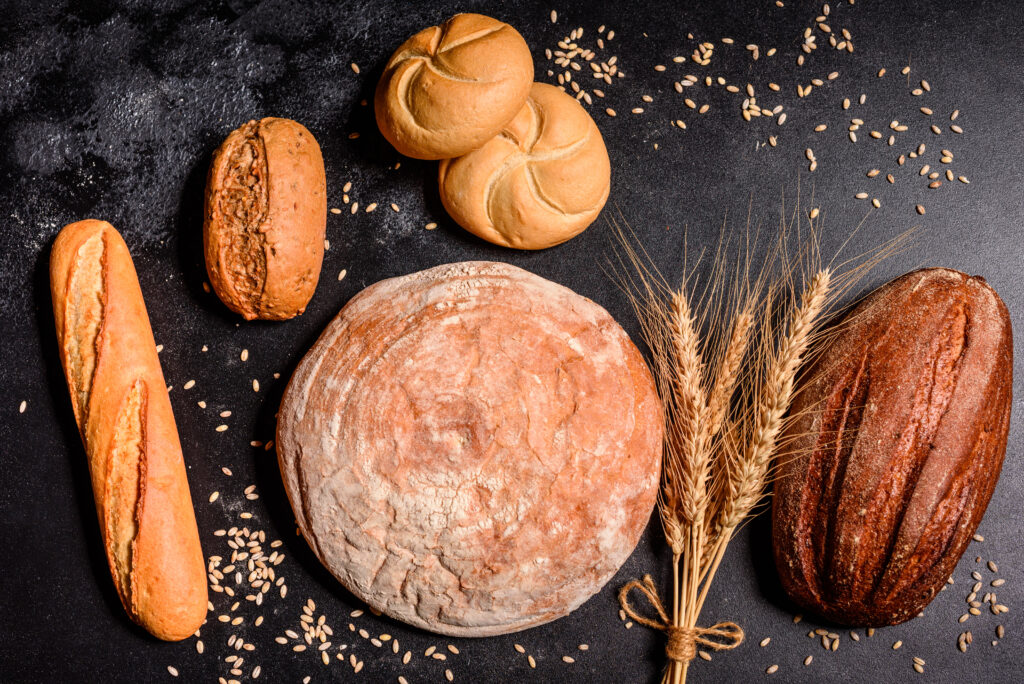 Beautiful fresh baked bread with wheat grains on a dark concrete background